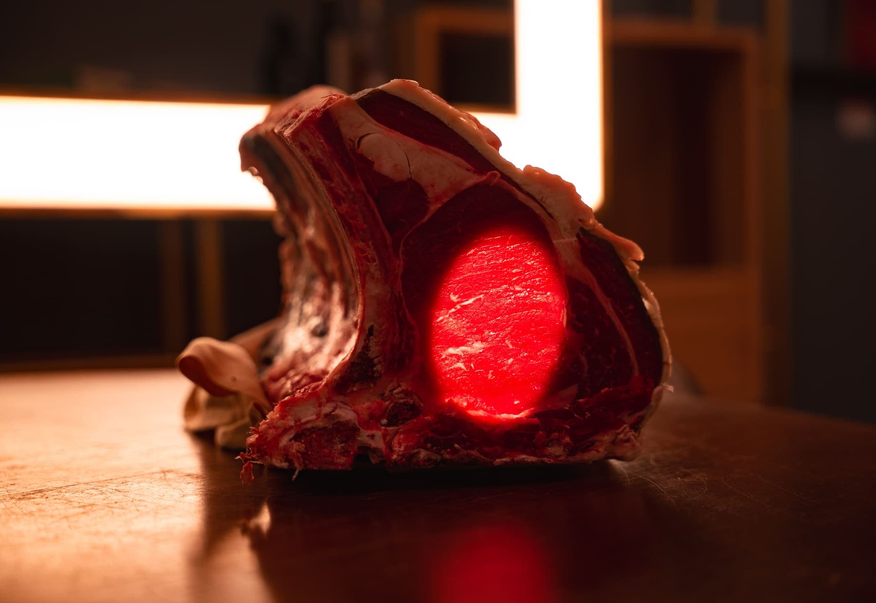 La costata frollata, in controluce davanti al neon della cantina